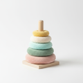 Soft pastel baby stacking rings in blush pink, sage green, mint, cream and yellow on a natural wooden post